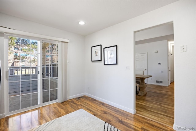 spare room featuring recessed lighting, wood finished floors, visible vents, and baseboards