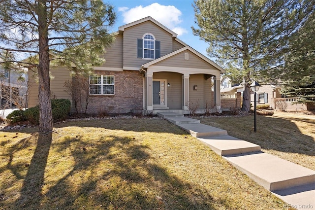 traditional-style home with covered porch, brick siding, and a front lawn