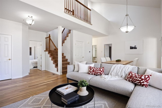 living room featuring stairs, a high ceiling, wood finished floors, and baseboards