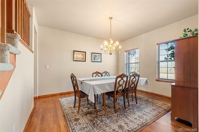 dining area with hardwood / wood-style floors and an inviting chandelier