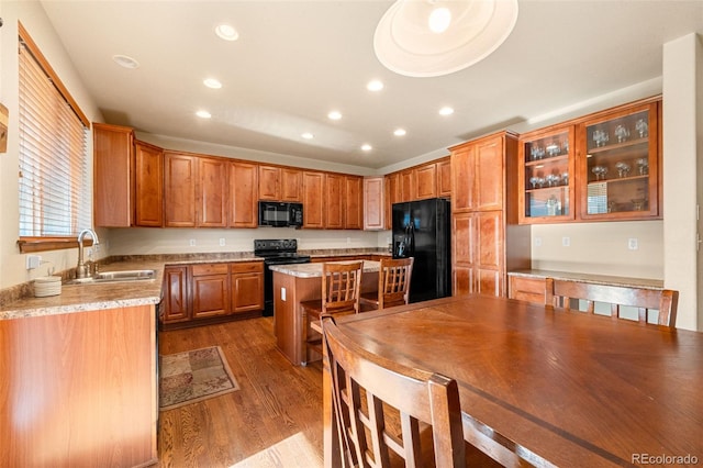 kitchen with black appliances, a kitchen island, sink, and hardwood / wood-style flooring