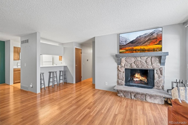 living room featuring a fireplace, wood-type flooring, and a textured ceiling