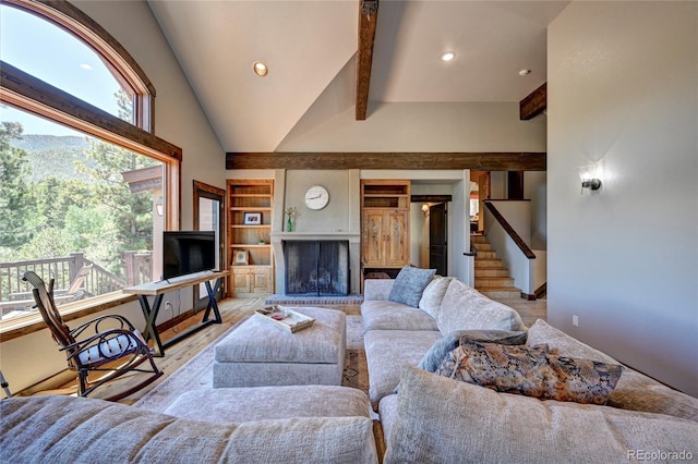 living room with high vaulted ceiling, beamed ceiling, a brick fireplace, and light hardwood / wood-style floors