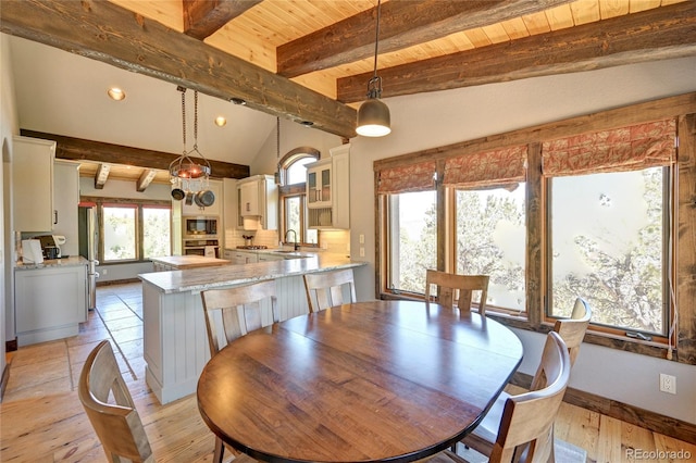 dining room featuring light hardwood / wood-style floors, lofted ceiling with beams, sink, and wooden ceiling