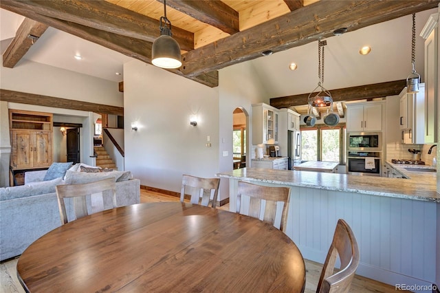 dining room with light hardwood / wood-style floors, lofted ceiling with beams, and sink