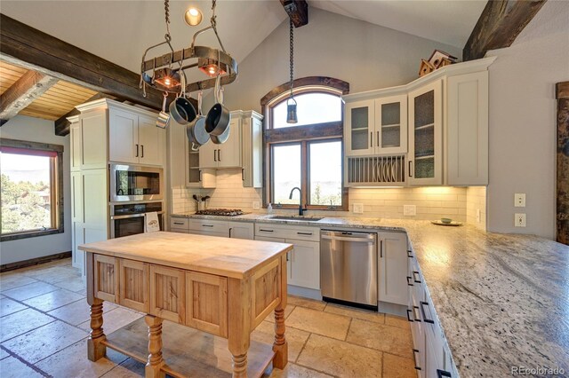 kitchen with light tile patterned flooring, decorative backsplash, sink, lofted ceiling with beams, and appliances with stainless steel finishes