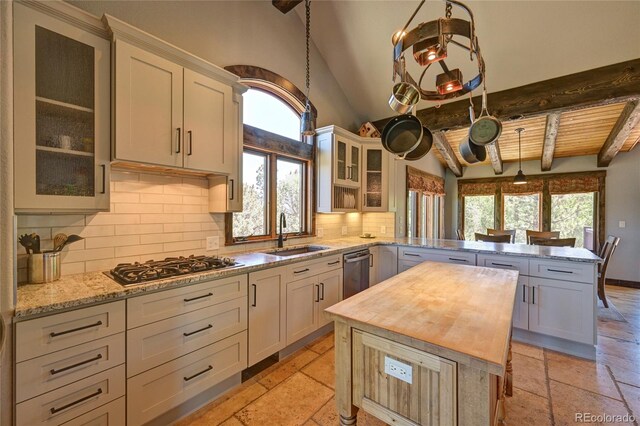 kitchen with beamed ceiling, a healthy amount of sunlight, light tile patterned floors, and backsplash