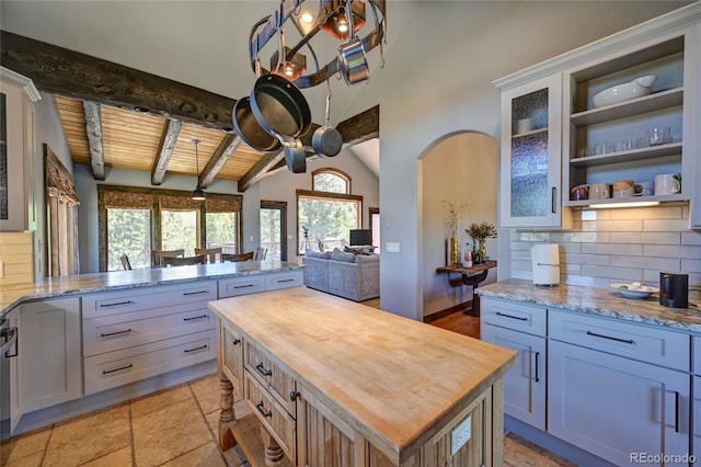 kitchen featuring light tile patterned floors, backsplash, wood ceiling, lofted ceiling with beams, and butcher block countertops