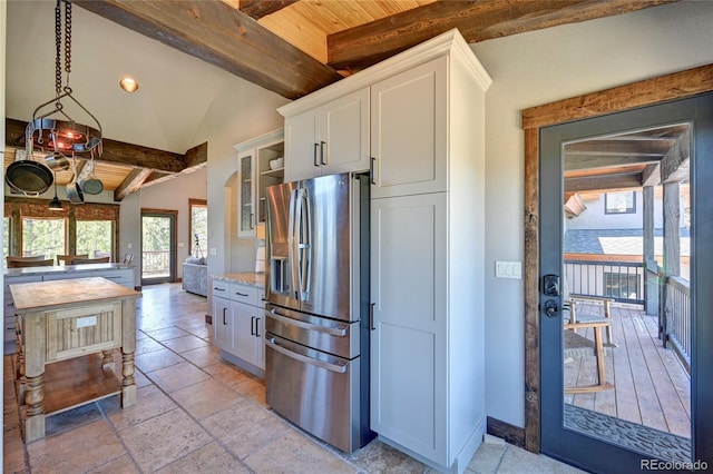 kitchen with lofted ceiling with beams, white cabinets, wood ceiling, light tile patterned floors, and stainless steel fridge with ice dispenser