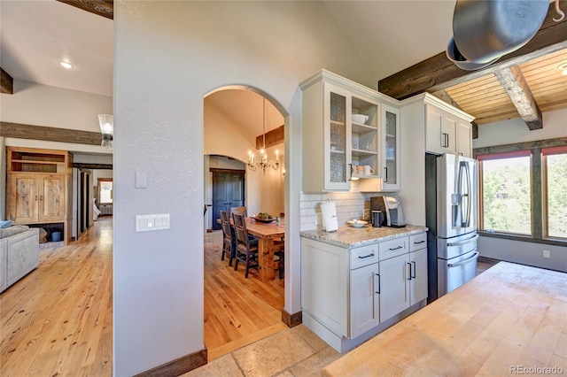 kitchen featuring lofted ceiling with beams, white cabinetry, light tile patterned floors, and stainless steel fridge with ice dispenser