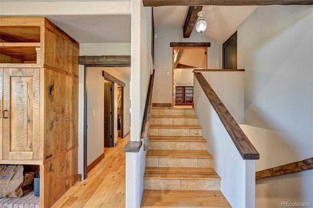 stairway featuring beam ceiling and light wood-type flooring