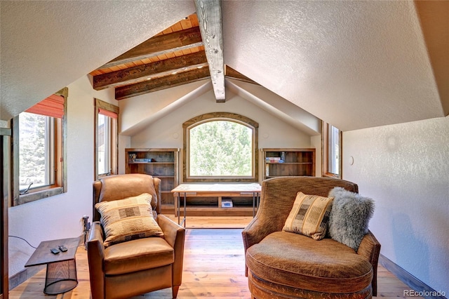 living area with a textured ceiling, hardwood / wood-style flooring, and vaulted ceiling with beams