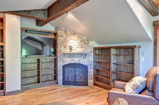 living room featuring vaulted ceiling with beams, a fireplace, a textured ceiling, and wood-type flooring