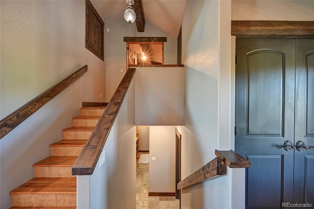 stairway featuring beamed ceiling