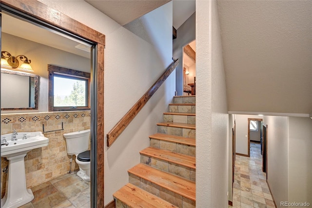 staircase with sink, light tile patterned floors, and tile walls