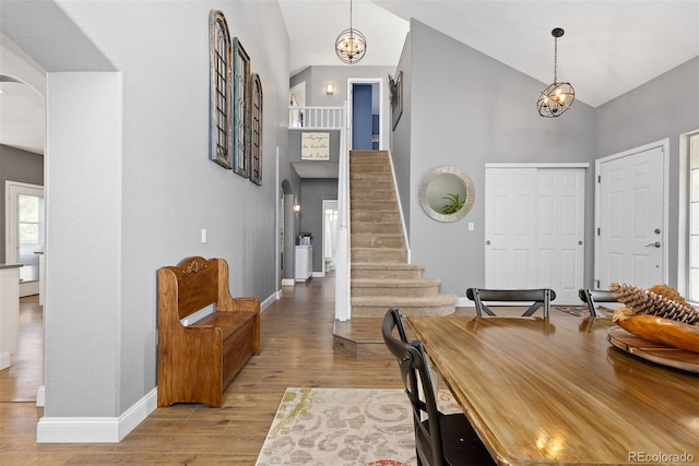 entryway with high vaulted ceiling, arched walkways, stairway, and wood finished floors