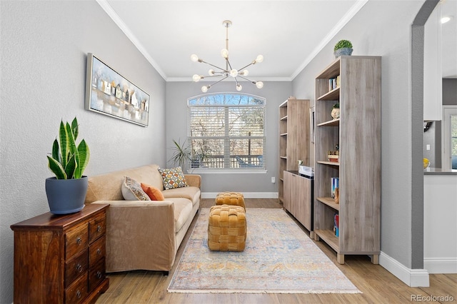 sitting room featuring light wood-type flooring, an inviting chandelier, baseboards, and ornamental molding