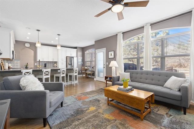 living area featuring a ceiling fan, arched walkways, dark wood-style flooring, and recessed lighting