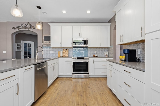 kitchen featuring backsplash, white cabinetry, stainless steel appliances, and a sink