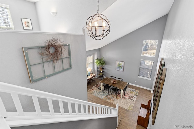 interior space featuring a wealth of natural light, a chandelier, vaulted ceiling, and wood finished floors