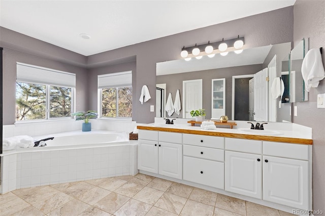 bathroom featuring a bath, double vanity, a sink, and a textured wall