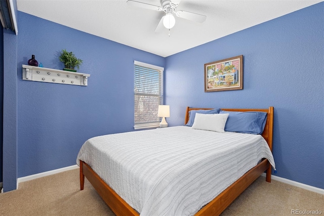 bedroom with a textured wall, carpet flooring, ceiling fan, and baseboards