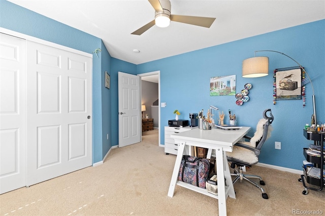 carpeted office space with ceiling fan and baseboards