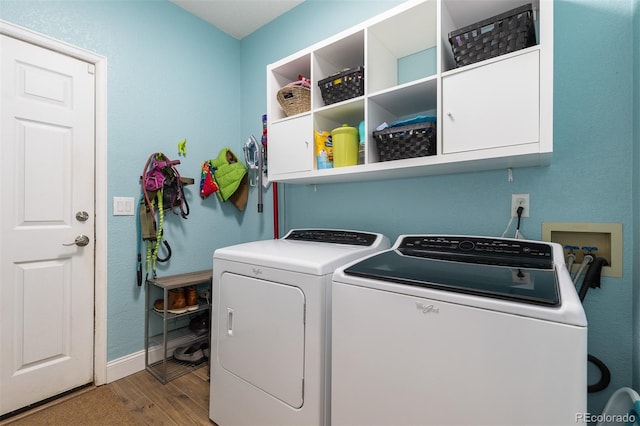 laundry area featuring cabinet space, baseboards, washer and dryer, and wood finished floors