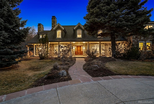 cape cod-style house with covered porch and a yard