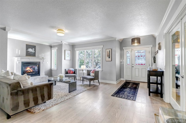 living area with crown molding, light wood-style flooring, a textured ceiling, and baseboards