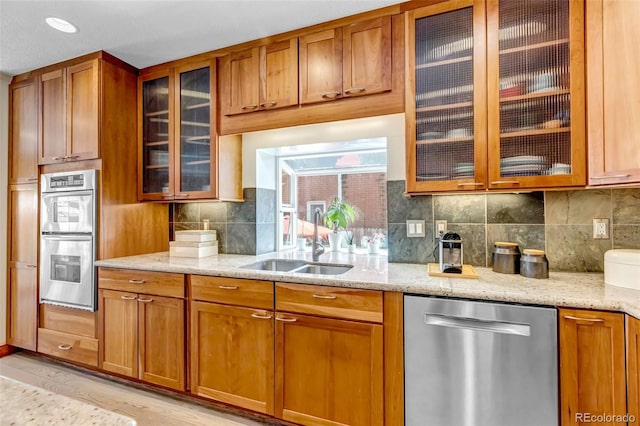 kitchen featuring a sink, light stone counters, brown cabinetry, and stainless steel appliances