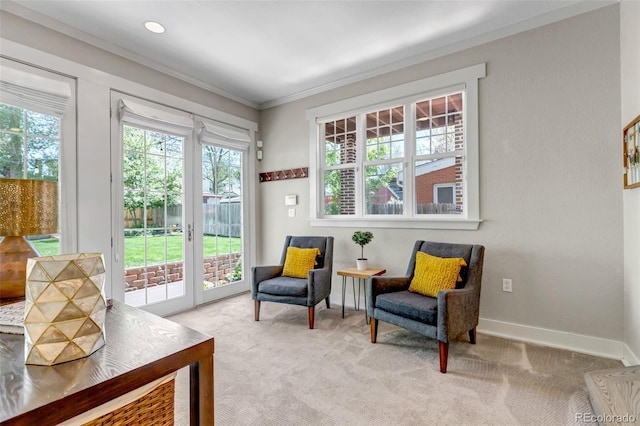 living area with crown molding, baseboards, and light carpet