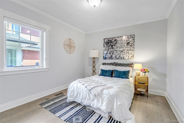 bedroom featuring crown molding, baseboards, and wood finished floors