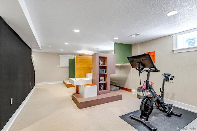 workout area featuring baseboards, recessed lighting, a textured ceiling, and visible vents