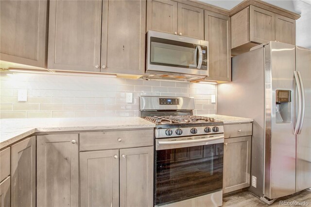 32 Trailside Cir Unit A, Salida, CO 81201 - kitchen featuring stainless steel appliances, light stone counters, backsplash, and light wood-style floors