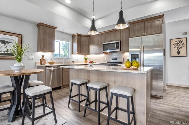 32 Trailside Cir Unit A, Salida, CO 81201 - kitchen featuring appliances with stainless steel finishes, light wood-style flooring, a kitchen island, backsplash, and a kitchen bar