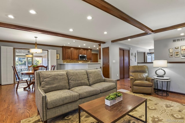 living area with recessed lighting, visible vents, beamed ceiling, and wood finished floors