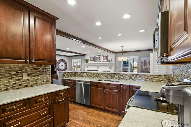 kitchen featuring stainless steel appliances, a sink, ornamental molding, light wood-type flooring, and backsplash