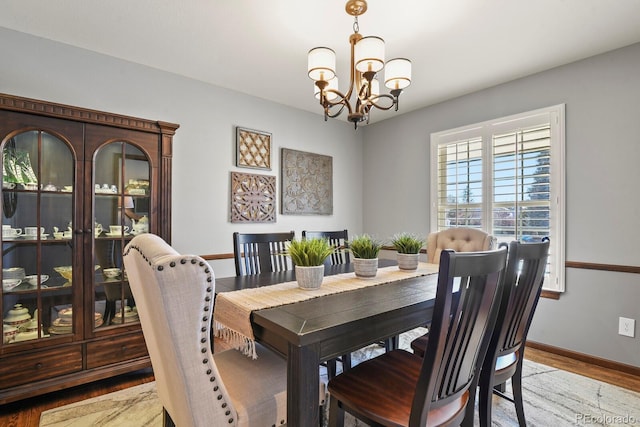 dining area featuring light wood-style floors, baseboards, and a notable chandelier