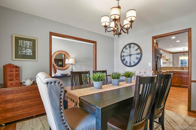 dining area featuring recessed lighting, light wood finished floors, and an inviting chandelier