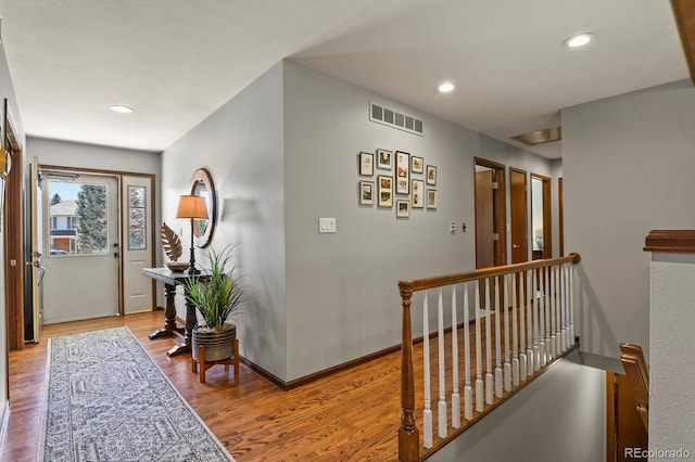 hall featuring baseboards, visible vents, wood finished floors, an upstairs landing, and recessed lighting