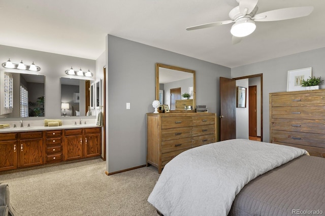 bedroom featuring light carpet, a sink, baseboards, and ensuite bathroom