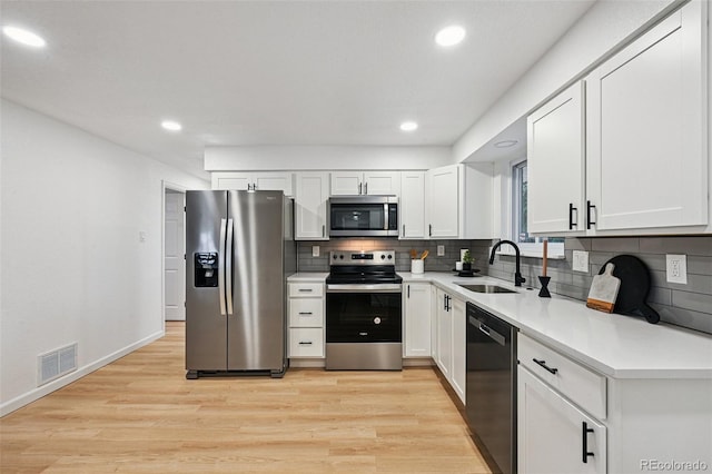 11176 W 62nd Ave, Arvada, CO 80004 - kitchen with appliances with stainless steel finishes, backsplash, light wood-type flooring, recessed lighting, and white cabinetry