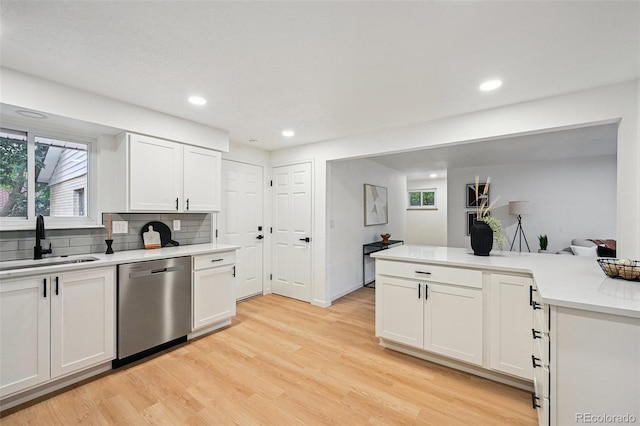 11176 W 62nd Ave, Arvada, CO 80004 - kitchen featuring stainless steel dishwasher, light wood-style floors, light countertops, tasteful backsplash, and white cabinetry