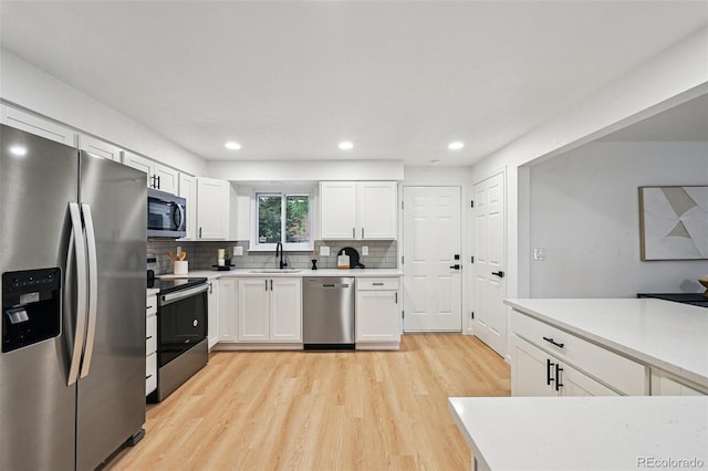 11176 W 62nd Ave, Arvada, CO 80004 - kitchen with stainless steel appliances, light wood-style flooring, white cabinets, light countertops, and recessed lighting