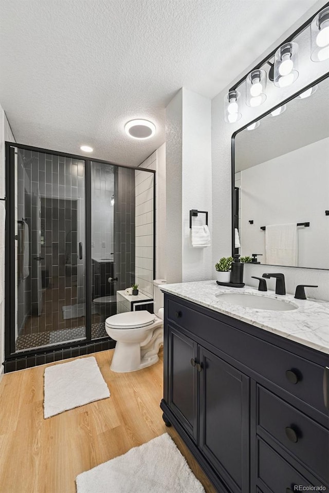 11176 W 62nd Ave, Arvada, CO 80004 - bathroom with a textured ceiling, wood finished floors, vanity, and a stall shower