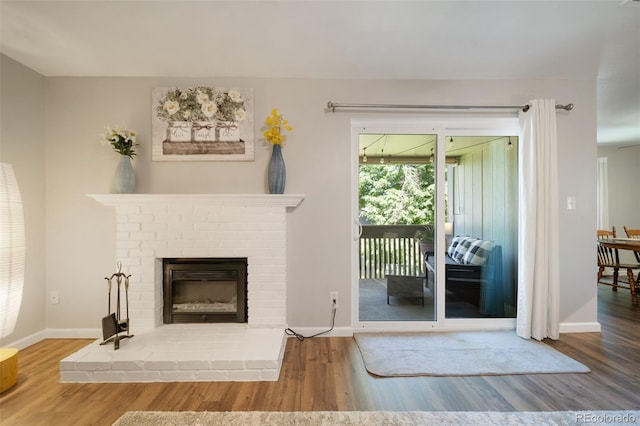 living room featuring wood-type flooring and a brick fireplace