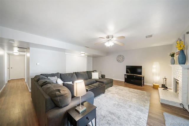 living room with ceiling fan, a fireplace, and light wood-type flooring