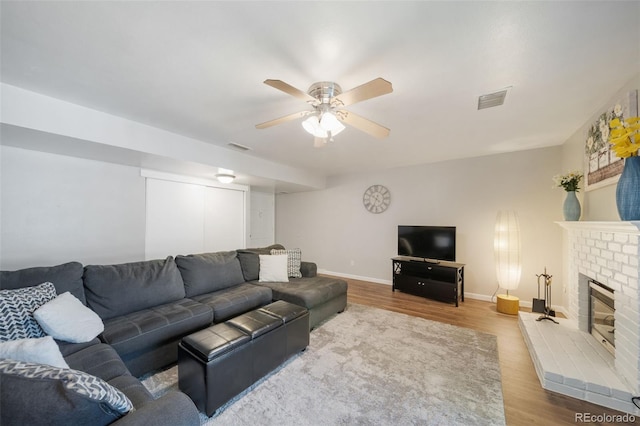 living room featuring hardwood / wood-style flooring, ceiling fan, and a fireplace