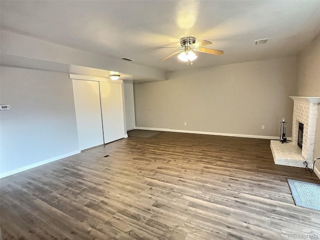 unfurnished living room featuring ceiling fan, dark wood-type flooring, and a fireplace